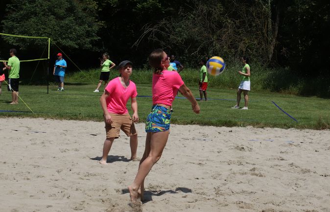 Beachvolleyballteam in pinken Trikots schlägt Ball am Netz